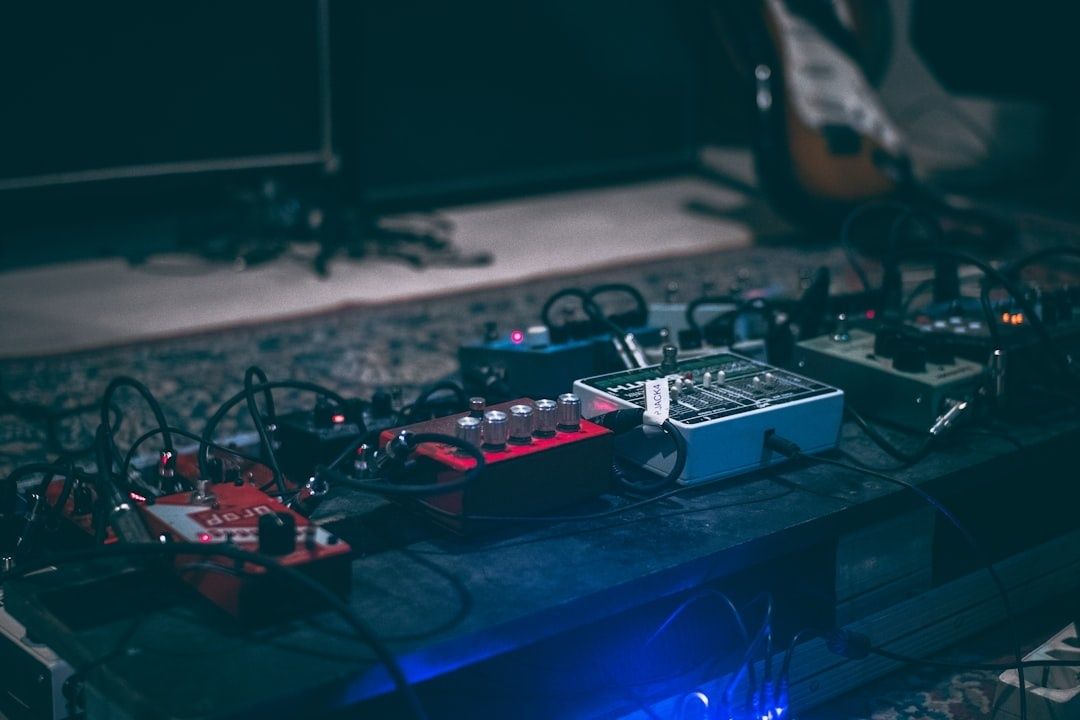 Electric guitar effects pedals and cables arranged on a dimly lit floor