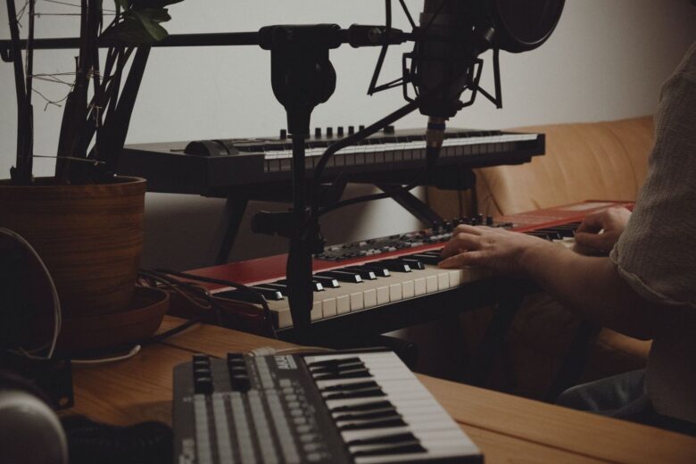 Musician playing a keyboard beside studio microphones and recording equipment