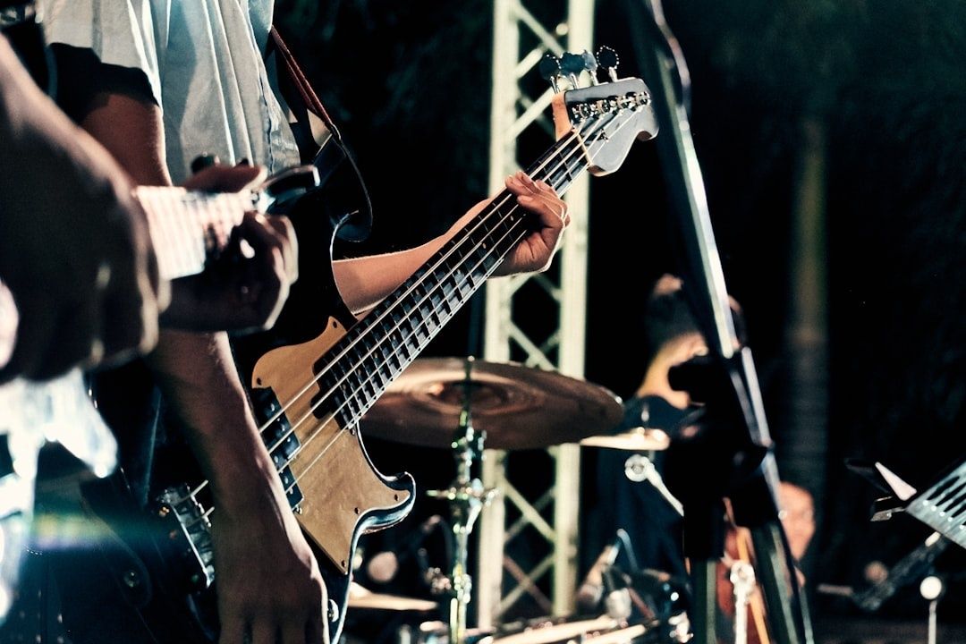 Close-up of bass guitar and drummer performing on a lit stage