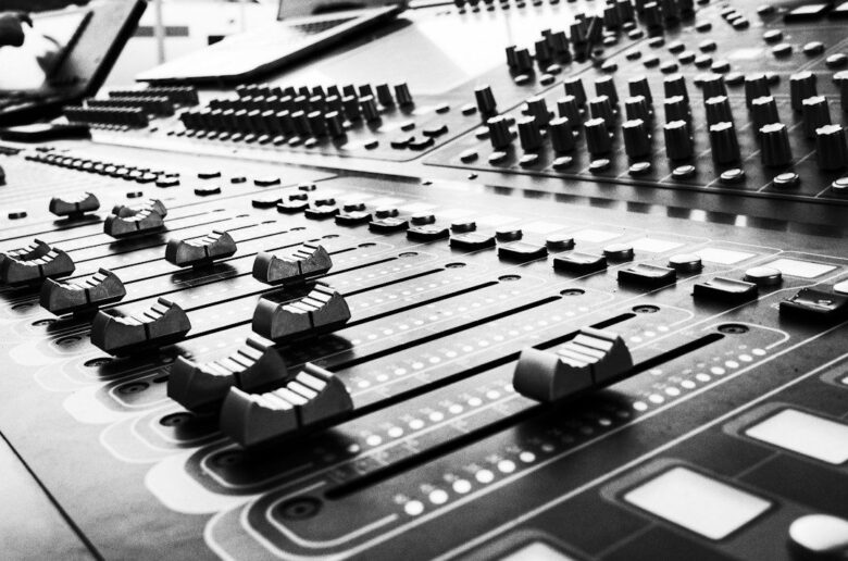 Close-up black-and-white view of an audio mixing console