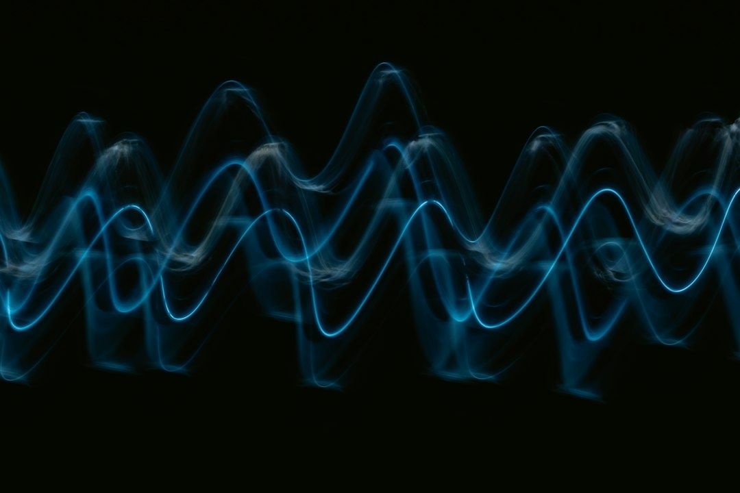 Glowing blue sound waves undulate across a black background